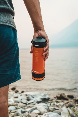 Lifesaver Liberty in Orange in der Hand eines Wanderers an einem See mit Kiesstrand
