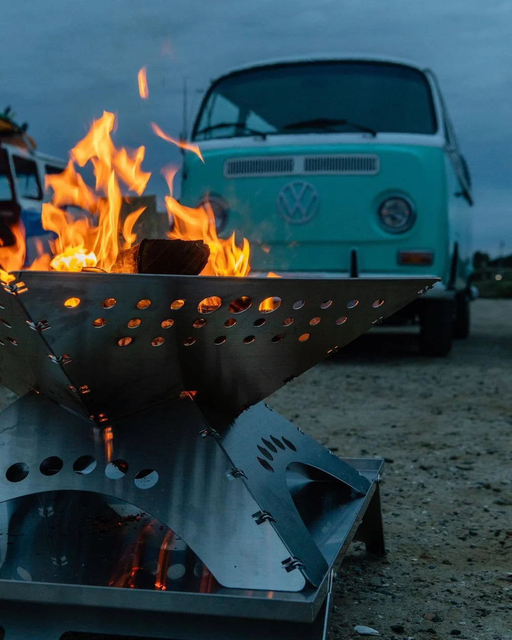 Winnerwell Flache Feuerschale mit hohen Flammen vor einem hellgrünen Volkswagen Bus