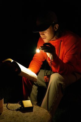 WakaWaka Connect Pro als Leselampe im Dunkeln, ein Mann liest ein Buch bei ihrem Licht