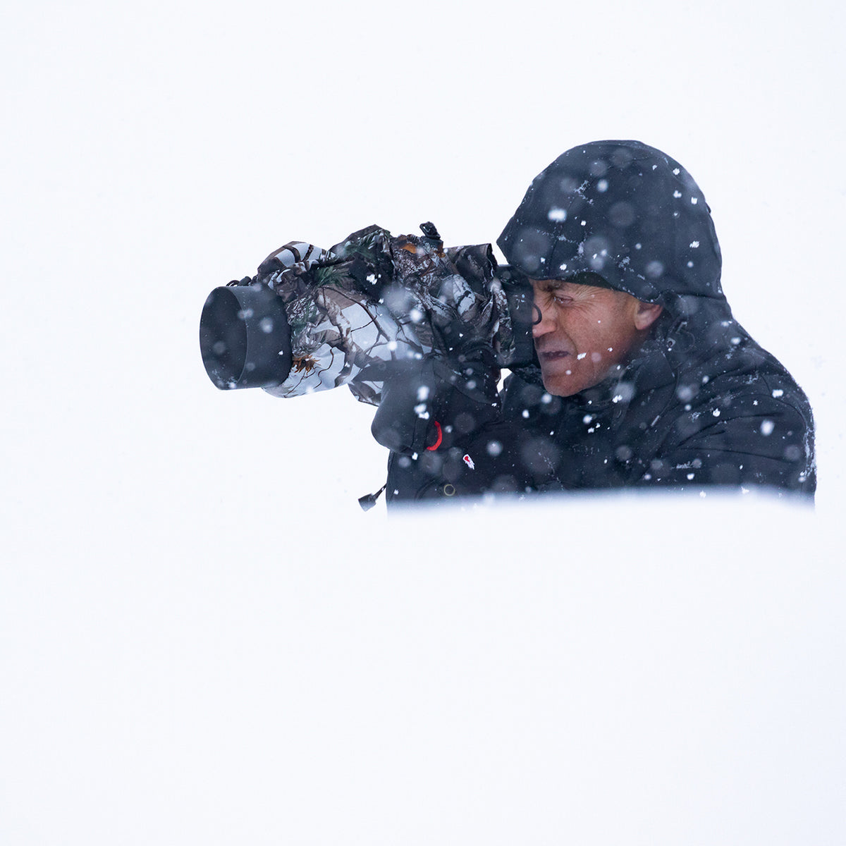 Buteo Regenschutz 1 im Einsatz, Fotograf mit Kamera und Objektiv unter der Hülle im Schnee