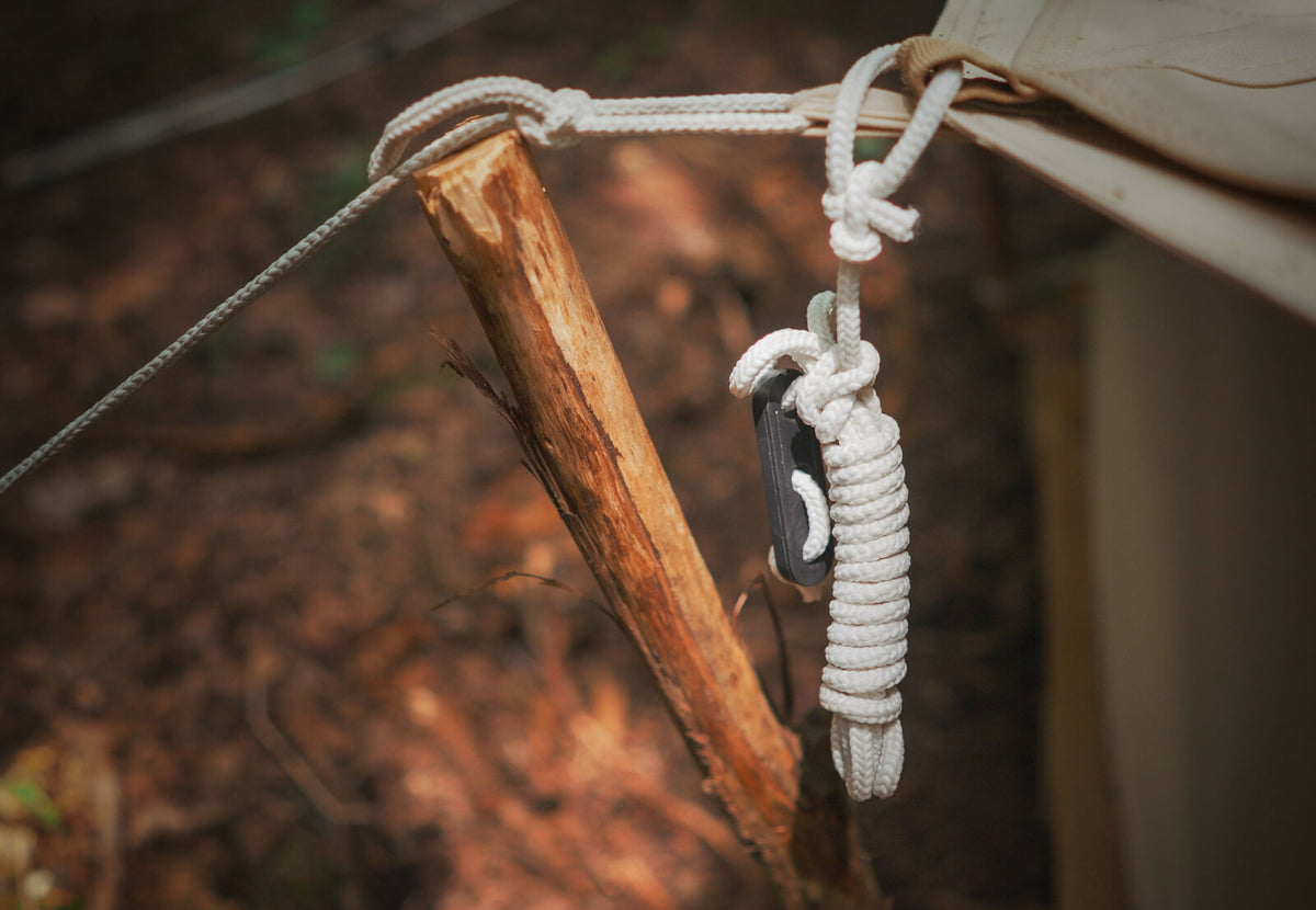 CanvasCamp Abspannleine mit Spanner an einem Holzpfahl aufgewickelt, neben dem Zelt