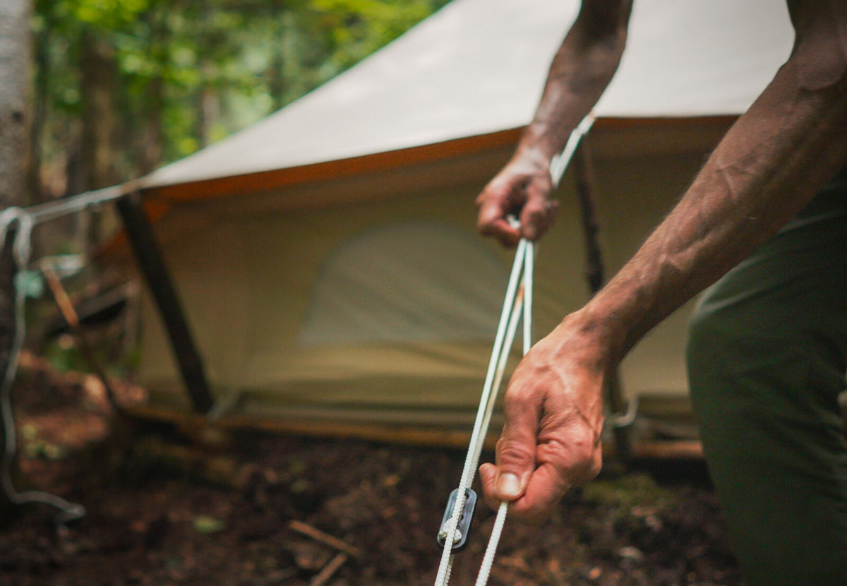 CanvasCamp Abspannleinen werden an einem Canvas-Zelt im Wald gespannt