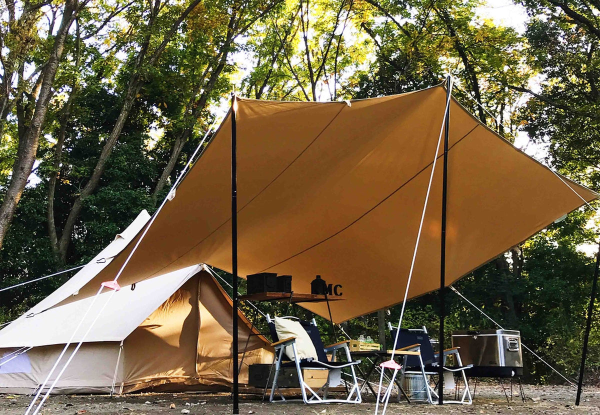CanvasCamp Classic All Purpose Shelter als ockerfarbenes Tarp an Stangen über Stühlen bei einem Glockenzelt