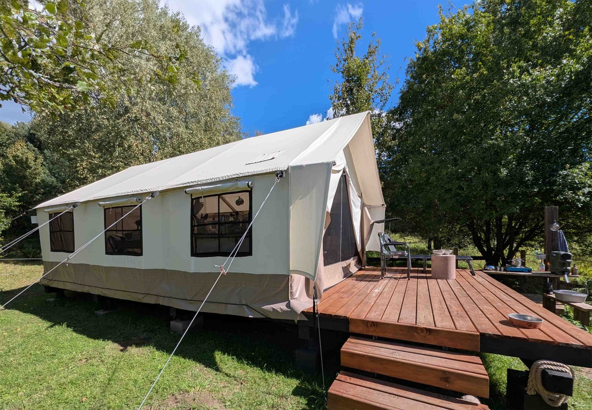 CanvasCamp Heavy Duty Safari Tent mit Holzterrasse und kleiner Treppe in einem sonnigen Garten