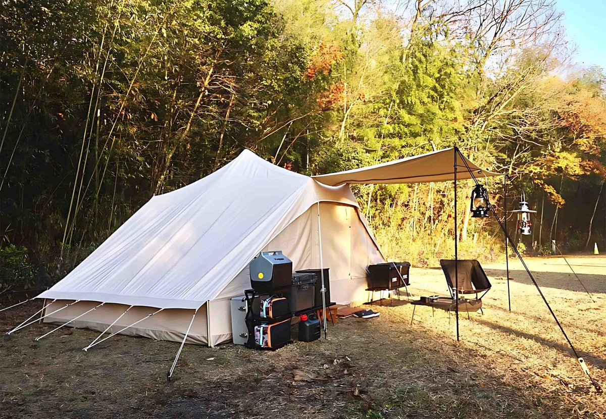 CanvasCamp Roman Traveller auf einem Stellplatz im Wald mit Vordach und Campingausrüstung