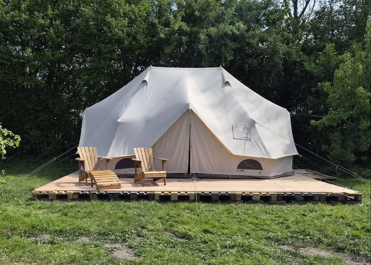 CanvasCamp Sibley Apex 600 Twin auf einem Holzdeck im Gras mit zwei Gartenstühlen aus Holz