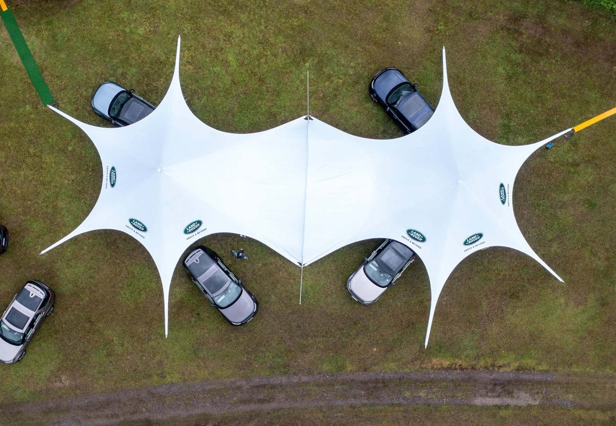 StarShade Connector verbindet zwei weiße StarShade Zelte, von oben gesehen auf einer Wiese
