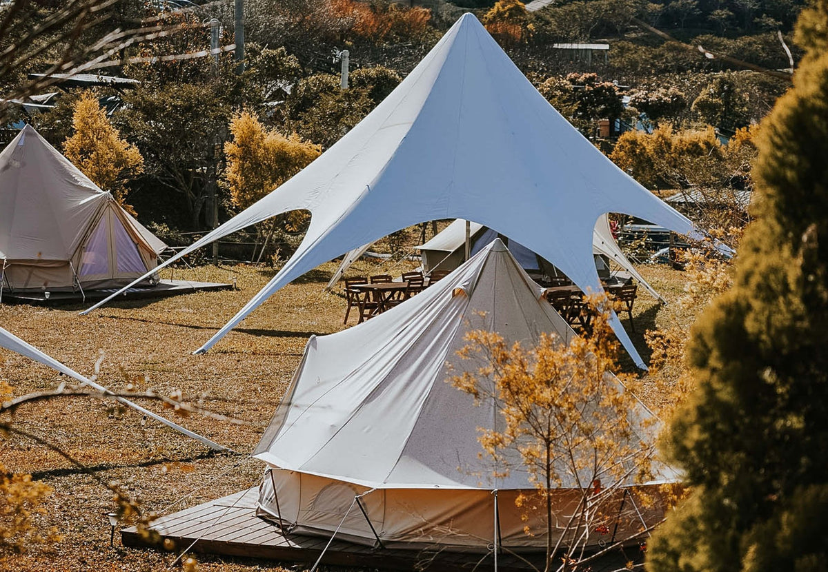CanvasCamp StarShade Eventzelt in Weiß über einem Glockenzelt auf einem Glampingplatz