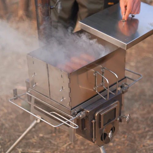 Winnerwell Flat Smoker im Einsatz auf einem Ofen, mit Rauch und Würstchen unter dem angehobenen Deckel