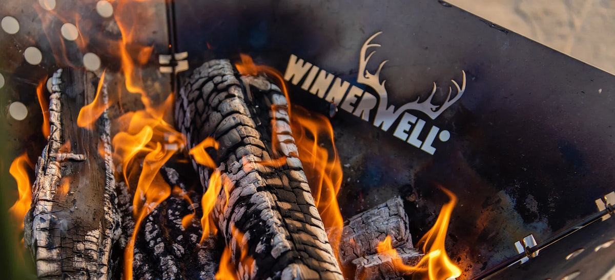 Winnerwell Feuerschale mit brennenden Holzscheiten und dem ausgeschnittenen Winnerwell Logo mit Geweih
