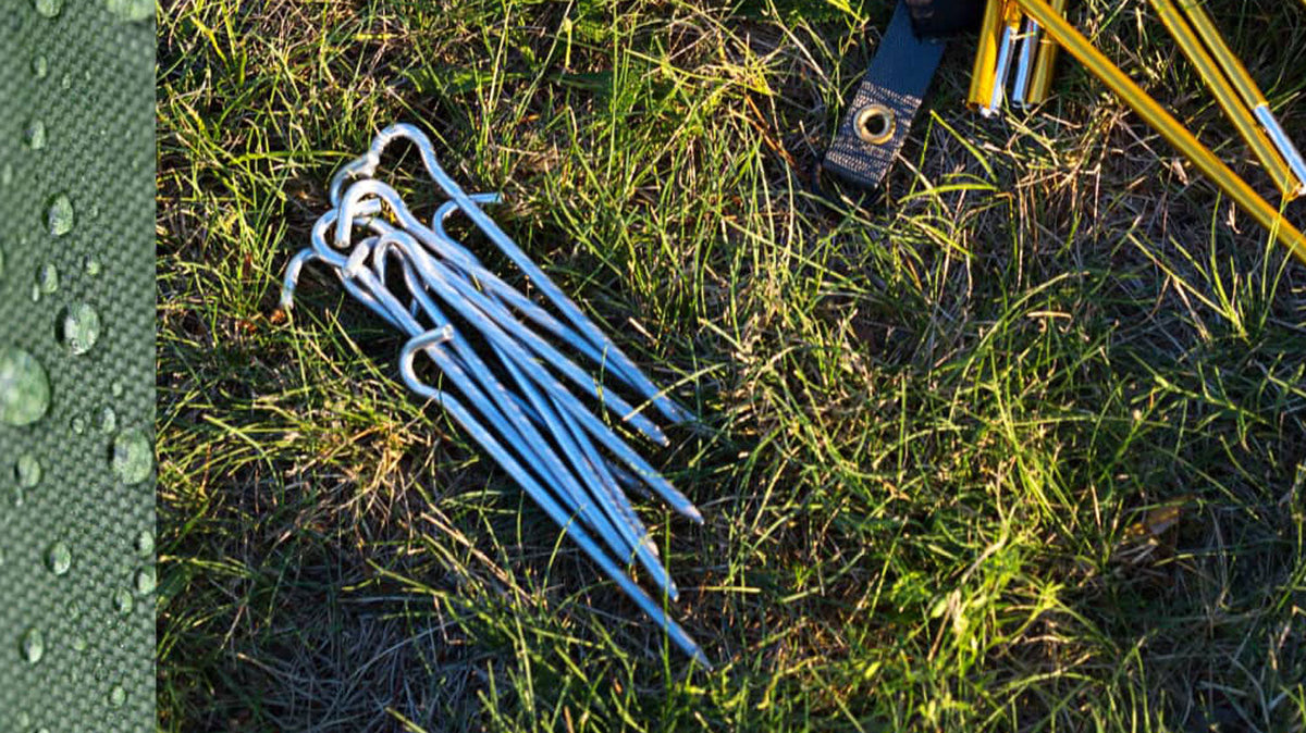 Zeltheringe, Bündel silberfarbener Heringe mit Haken im Gras neben einer gelben Zeltstange