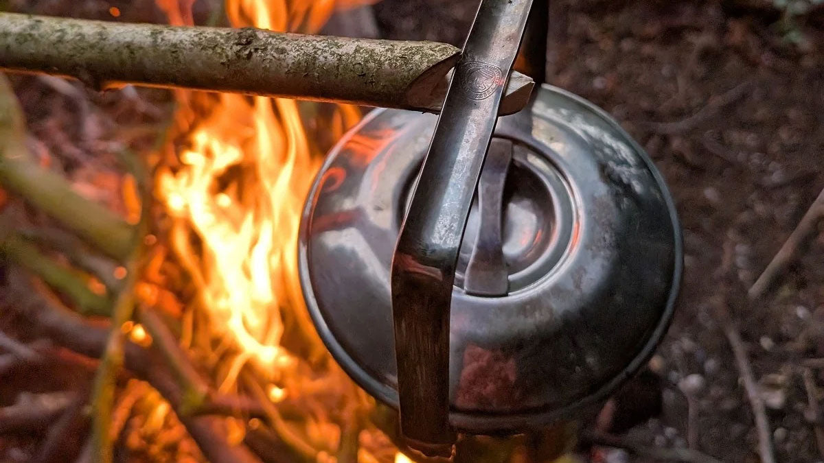 Zebra Thailand Kessel mit Henkel an einem Holzstock über einem brennenden Lagerfeuer