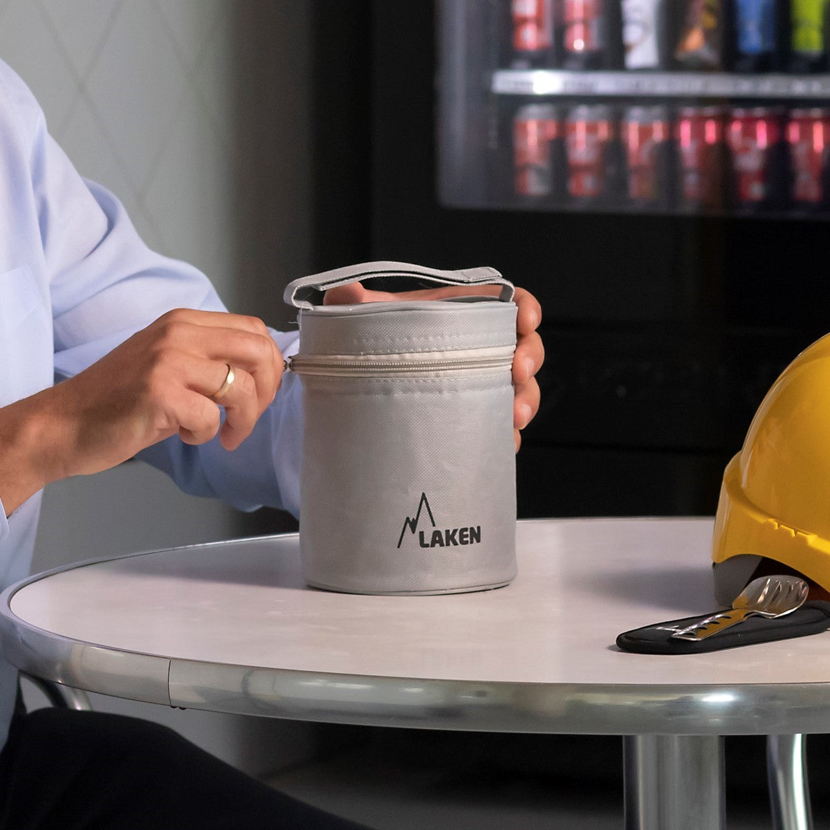 Laken Thermo Lunchbox in der grauen Tragetasche auf dem Tisch, neben einem gelben Bauhelm