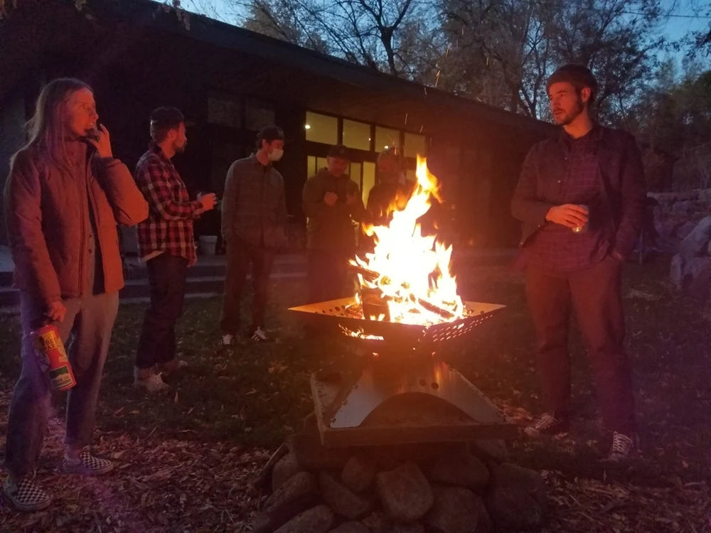 Winnerwell Flache Feuerschale mit Feuer am Abend inmitten einer kleinen Gruppe von Menschen
