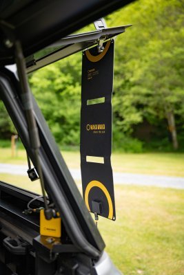 WakaWaka Solar 20 an der offenen Heckklappe eines Autos hängend, mit einer gelben Powerbank darunter
