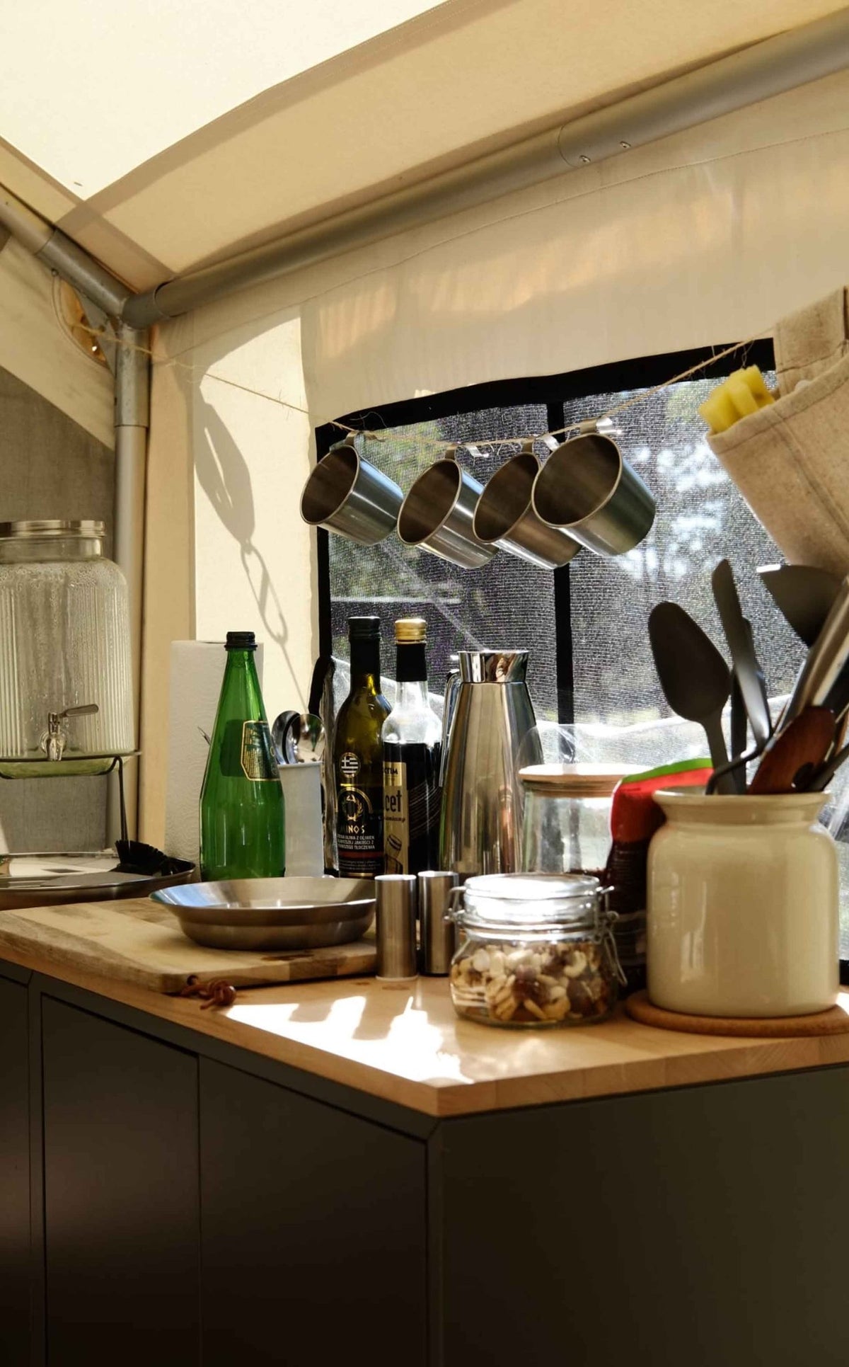 CanvasCamp Heavy Duty Safari Tent mit Küchenzeile und hängenden Pfannen vor dem Fenster eingerichtet