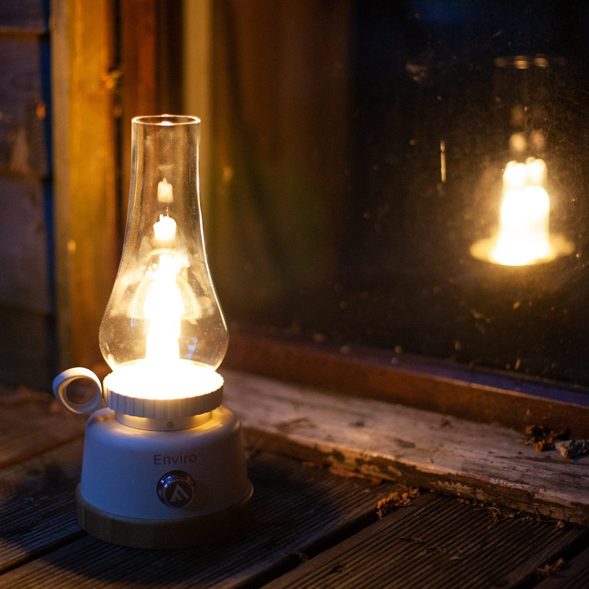 Mactronic Enviro Tischlampe leuchtend im Dunkeln an einem Fenster mit Spiegelung