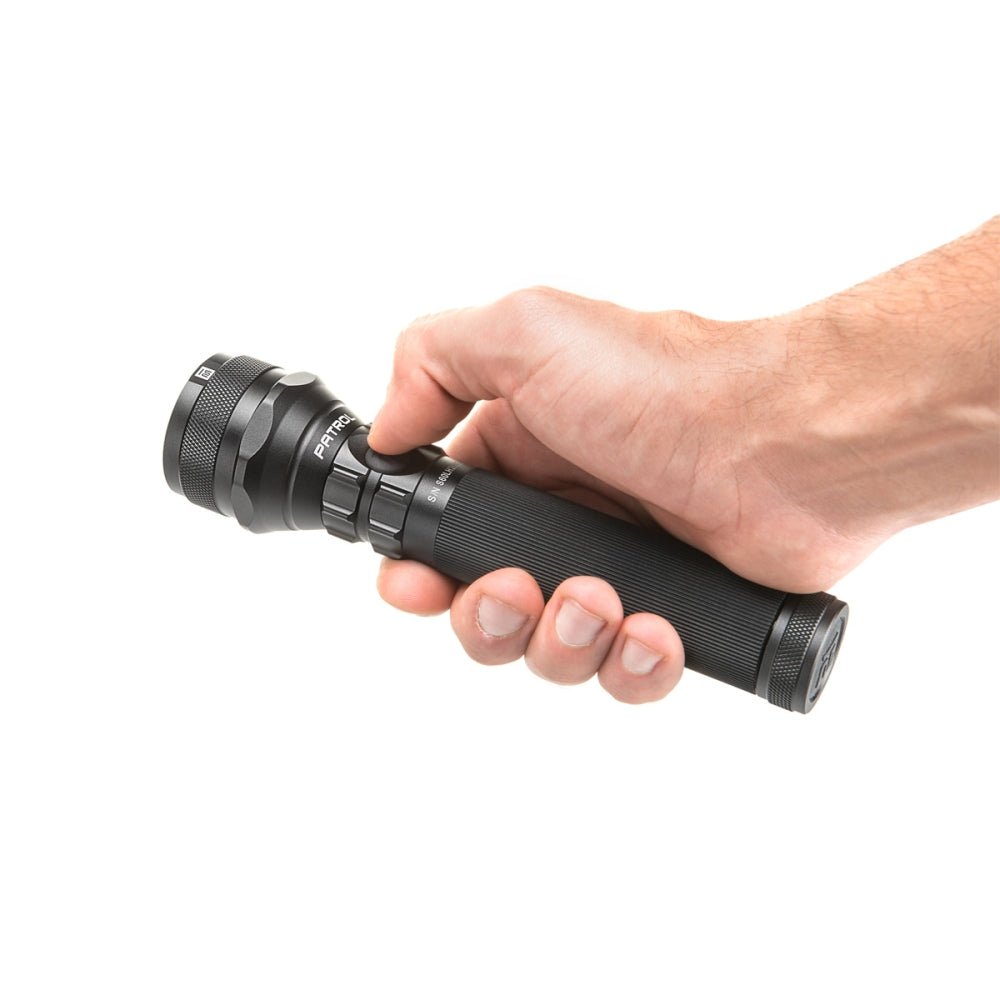 Mactronic Patrol Taschenlampe in einer Hand, mit dem Daumen beim Knopf am Lampenkopf