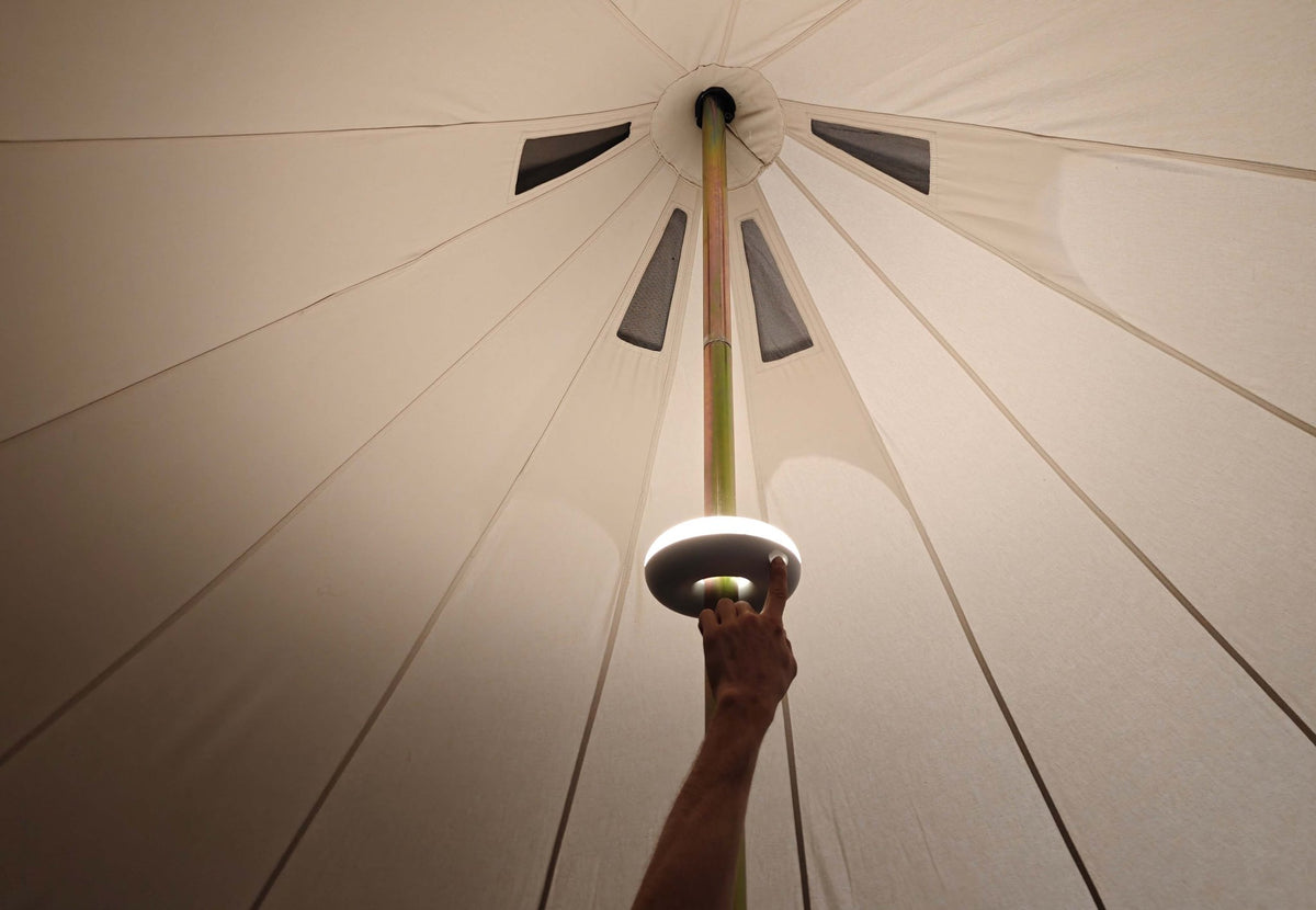 Aufladbare Zeltbeleuchtung, leuchtende Ringlampe wird von Hand um die Zeltstange geschoben
