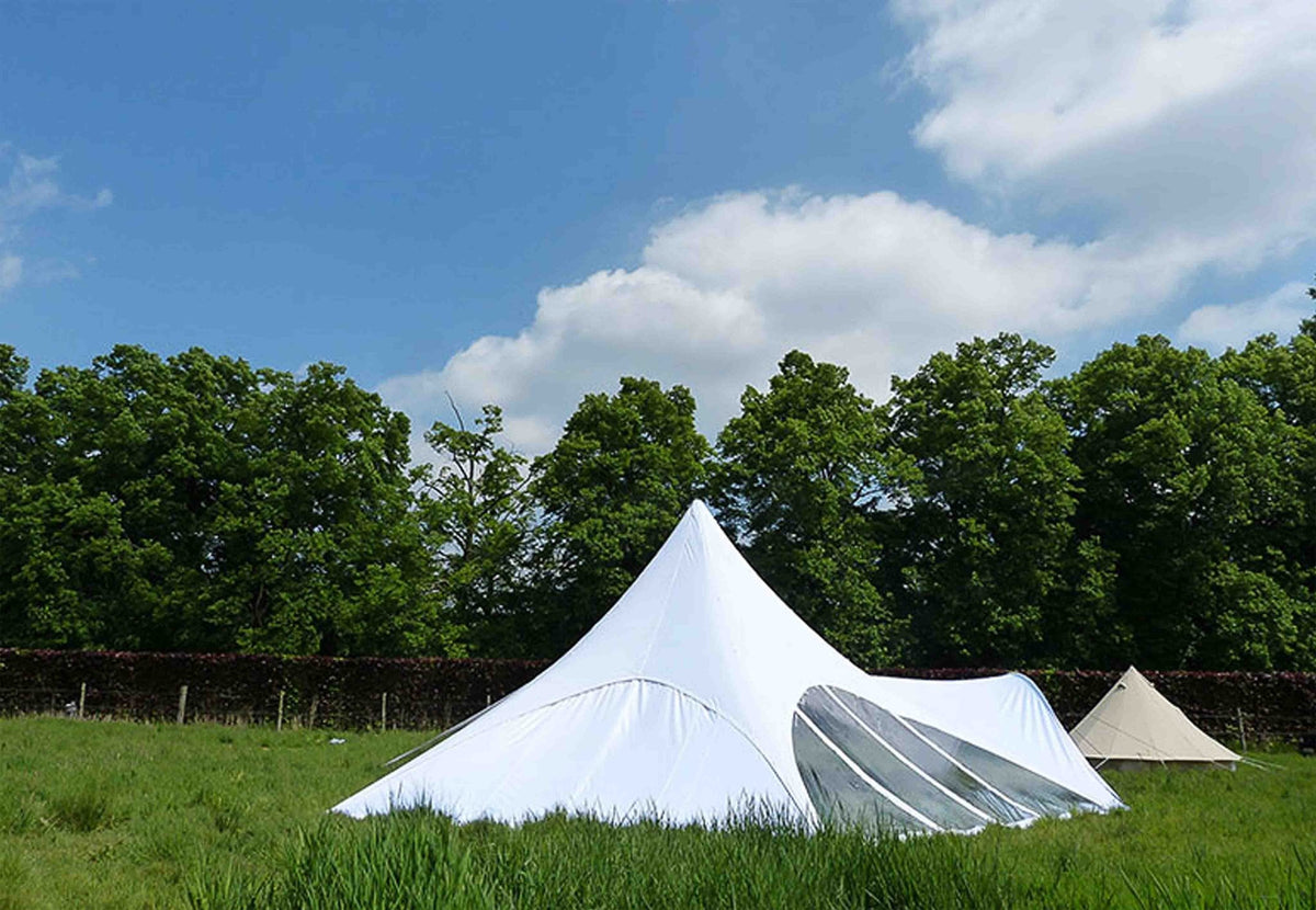 CanvasCamp StarShade Seitenteil an einem weißen Zelt, von weiter weg auf der Weide gesehen