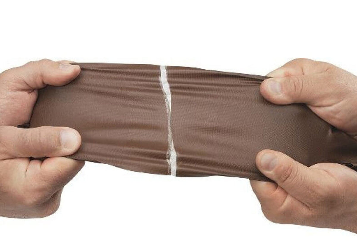 Tear-Aid B Reparatur auf braunem Material, das mit zwei Händen gedehnt wird
