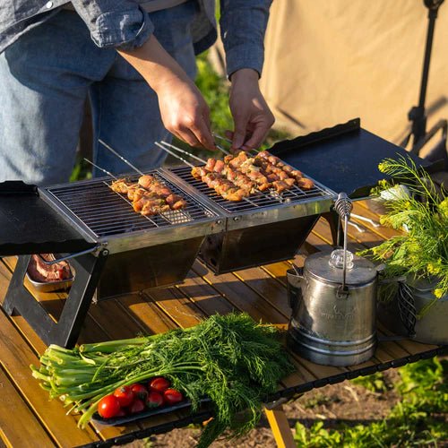 Winnerwell Campingtisch im Einsatz als Holzkohle BBQ mit Spießen auf dem Grill im Freien